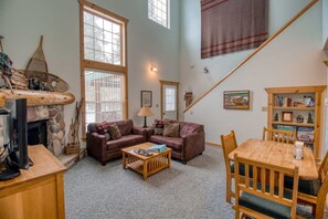 A cozy living room with a fireplace, two sofas, a coffee table, and a dining table with chairs.