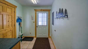 Un pasillo con una puerta de madera, un felpudo, un adorno en la pared y un interruptor de luz.