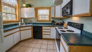 Una cocina con armarios blancos, estufa, microondas y lavavajillas.