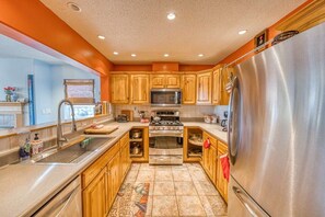 A kitchen with wooden cabinets, stainless steel appliances, and a tiled floor. - 3BR - Hot Tub, Jacuzzi, Stunning Mt. Elbert Views (Leadville)