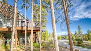 A rustic cabin with a wooden deck, surrounded by tall pine trees. - 3BR - Hot Tub, Jacuzzi, Stunning Mt. Elbert Views (Leadville)