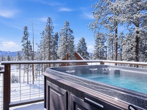 A hot tub on a deck with a view of snow-covered trees and mountains. - 3BR - Hot Tub, Jacuzzi, Stunning Mt. Elbert Views (Leadville)