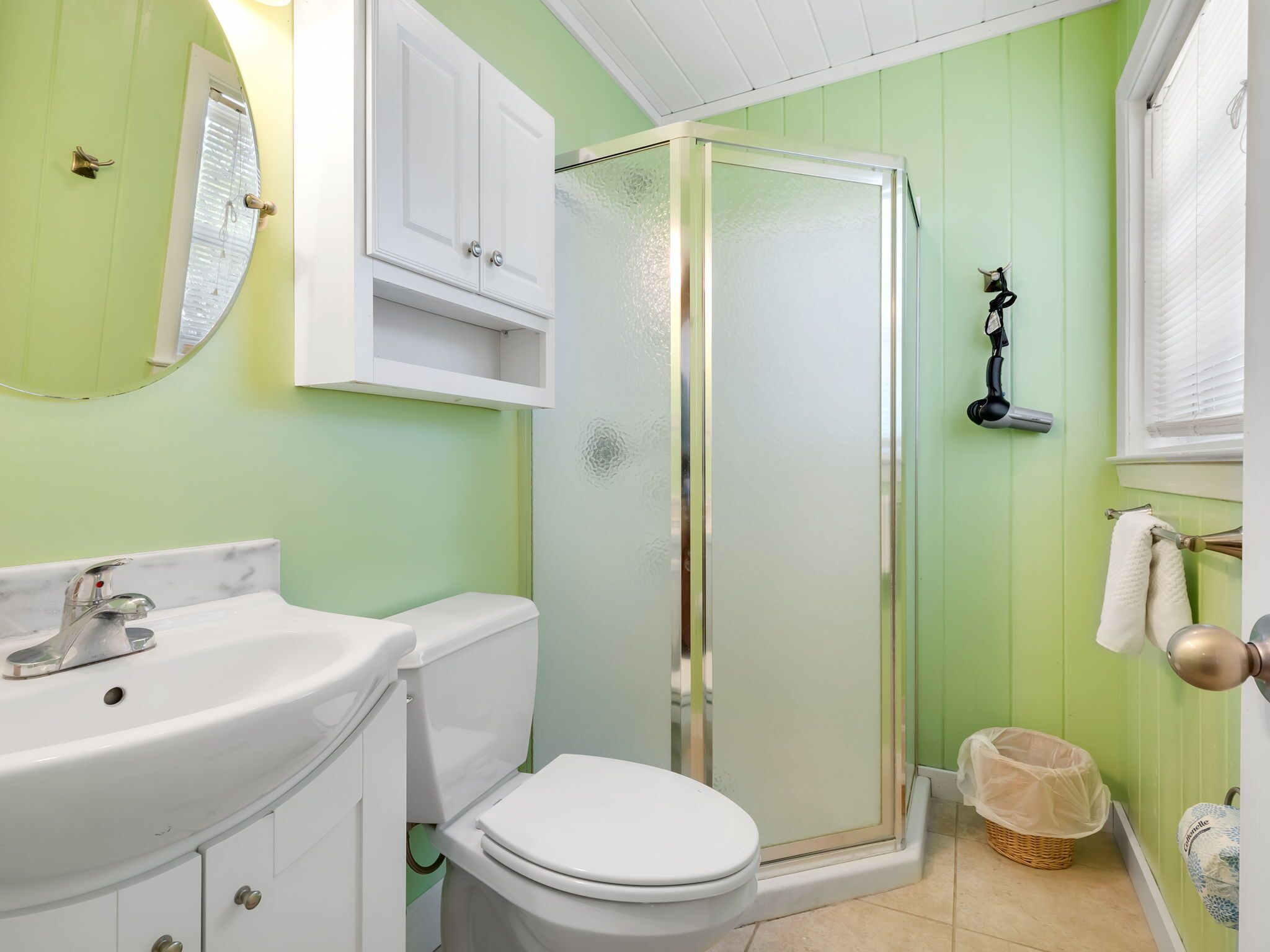 A bathroom with a white sink, toilet, and glass shower enclosure.