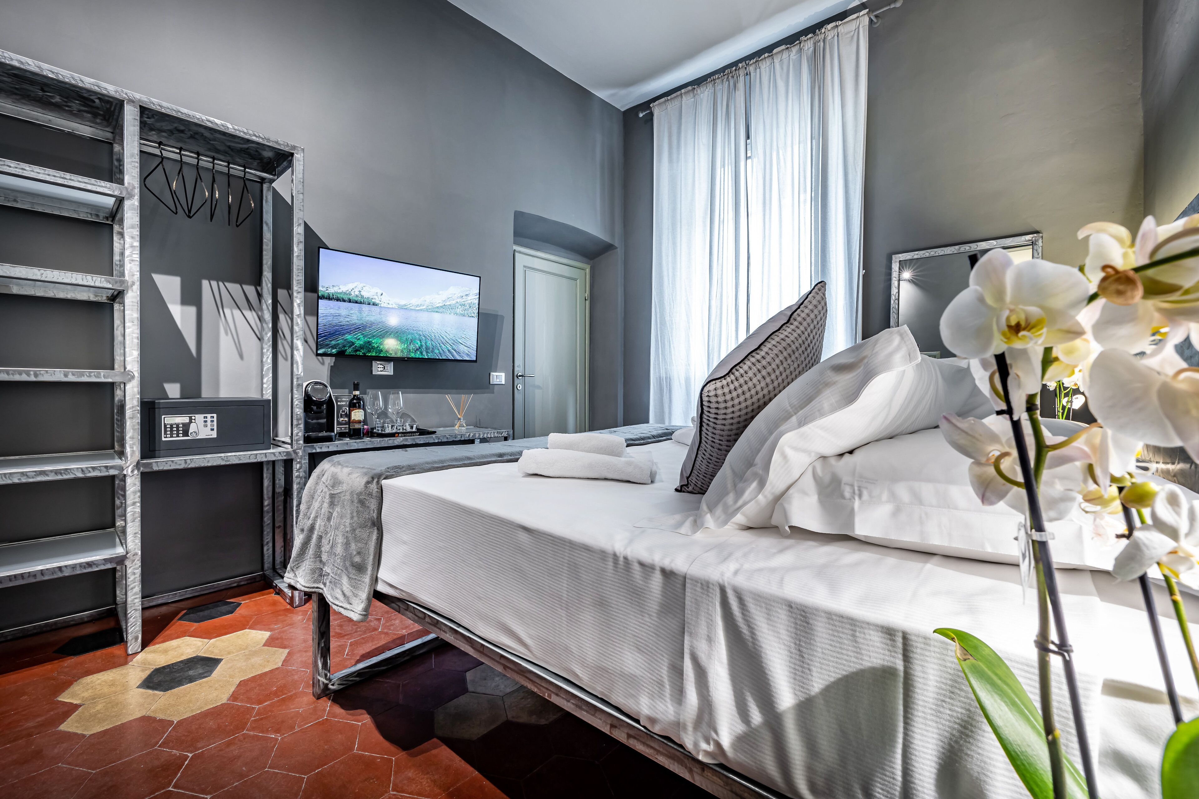 Una camera d'albergo moderna con un letto, una TV, un armadio e un angolo studio.