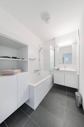 A modern bathroom with a built-in shower, a vanity with a mirror, and a toilet.