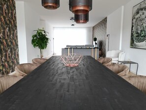 A modern dining area with a long table, cushioned chairs, and pendant lighting. - Lakeview Penthouse: Terrace, Free Parking, (Gmunden)