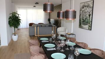 Een moderne eetruimte met een lange tafel gedekt voor zes personen, omringd door fauteuils.