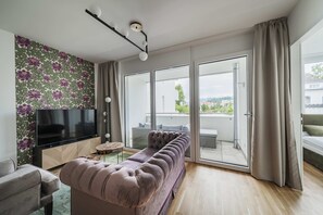 Un salon moderne doté d’un téléviseur à écran plat, d’un canapé, d’une table basse et d’une porte-fenêtre coulissante donnant sur un espace extérieur.