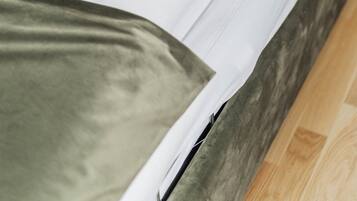 Una cama con ropa de cama blanca y una almohada verde.