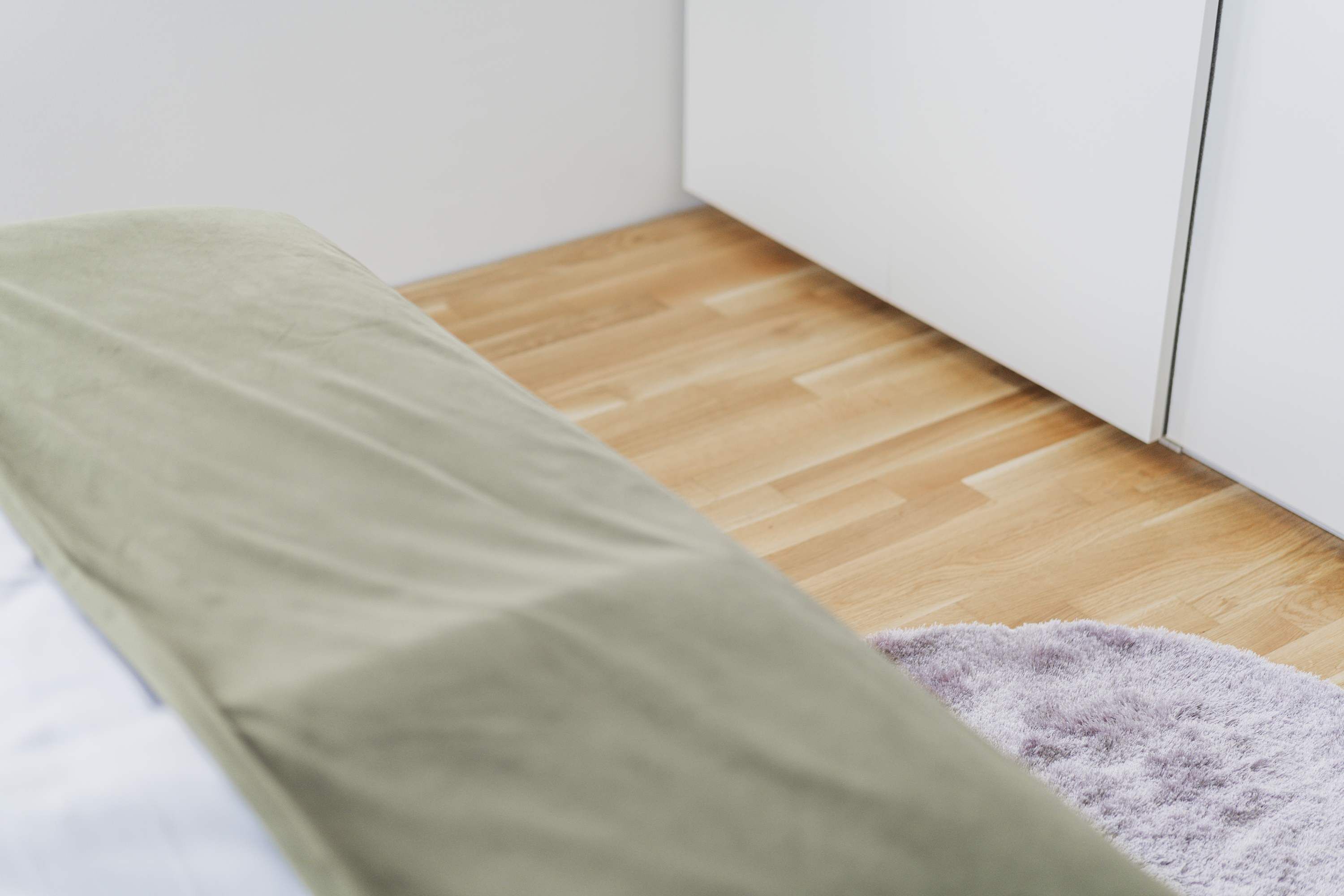 A room with a bench, a wooden floor, and a white wall.