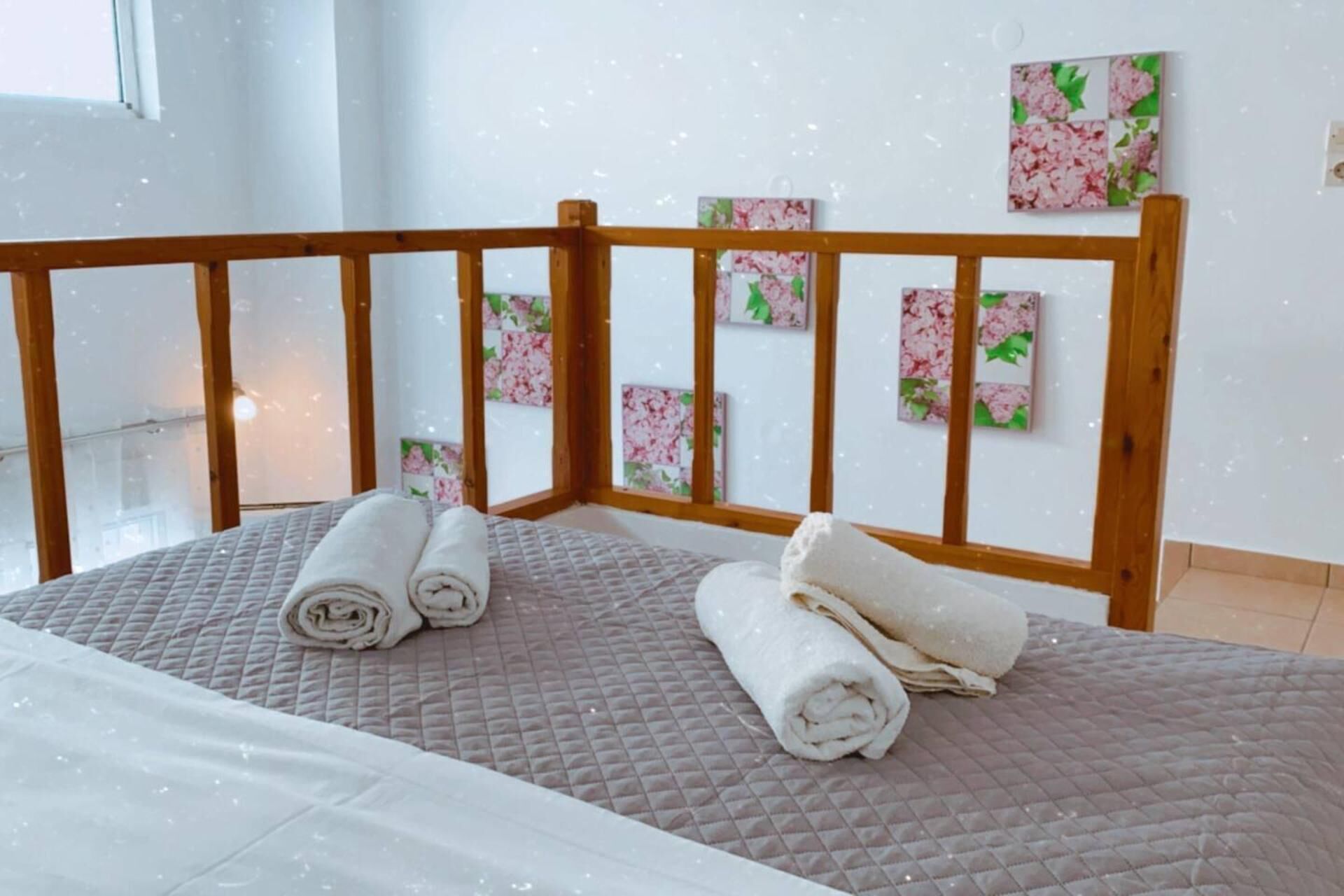 Una cama con colchón acolchado, cabecera de madera y toallas enrolladas.