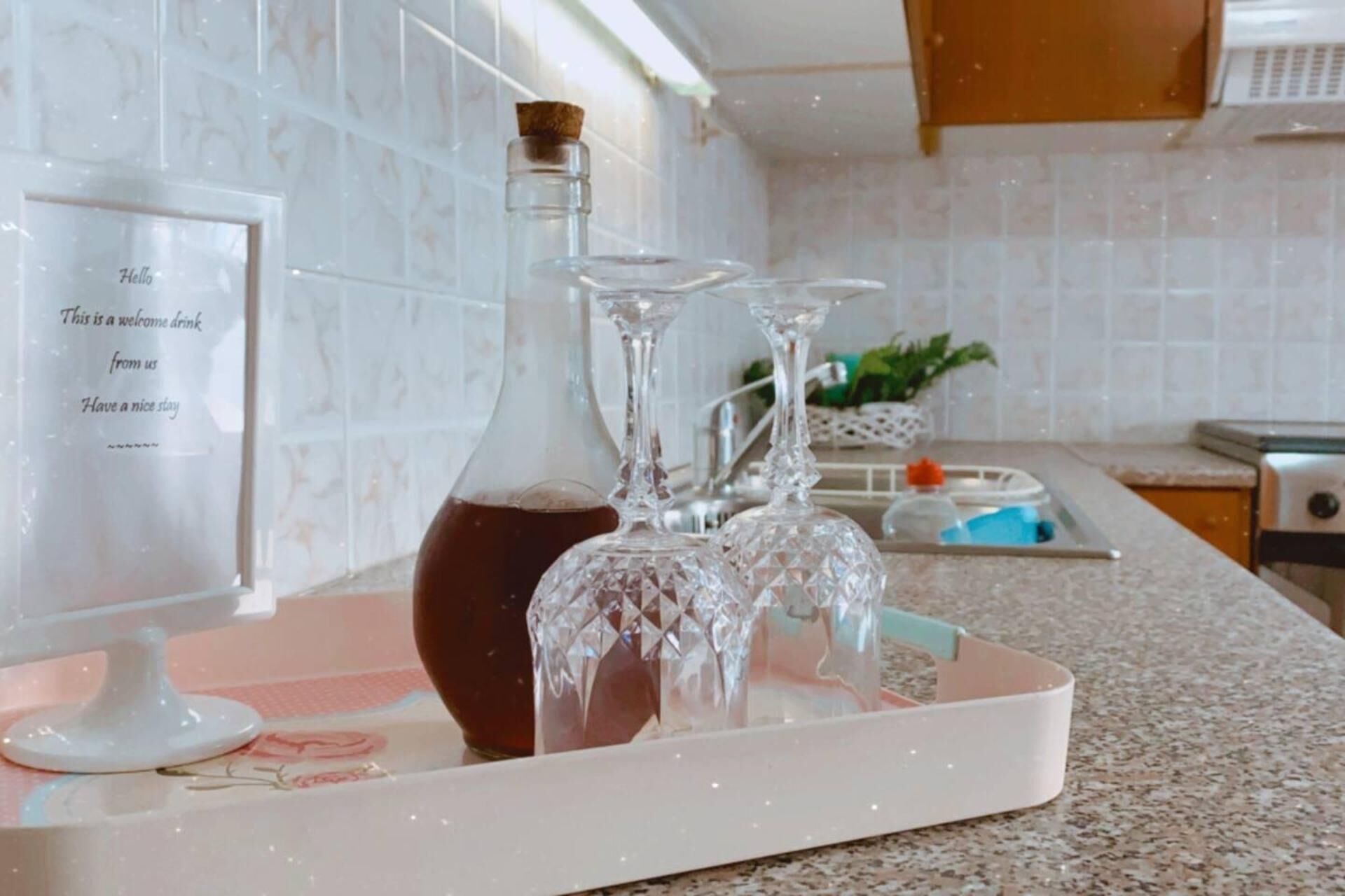 Eine Küchenarbeitsplatte mit einer dekorativen Tablett, auf dem eine Flasche und zwei Kristallgläser stehen.