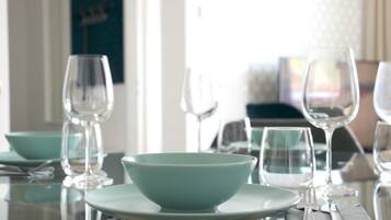 A dining table set with clear glassware and teal-colored bowls and plates.