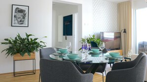 Un espace repas moderne avec une table en verre, des bols turquoise et des chaises grises.