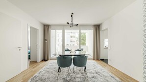 Een moderne woonkamer met een glazen tafel, twee stoelen, een pluizig vloerkleed en een plafondlamp.