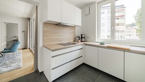 Een moderne keuken met witte kasten, een houten aanrechtblad en een groot raam.
