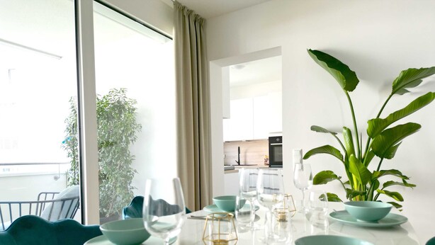Een eethoek met een tafel voor vier personen, een potplant en uitzicht op de keuken.