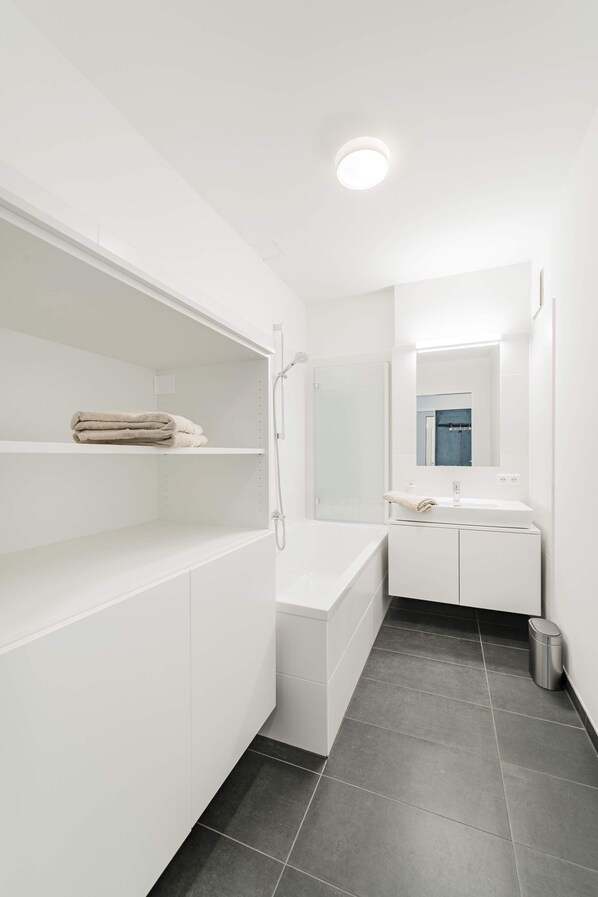 Un bany modern amb banyera, dutxa, rentapous i mirall.
