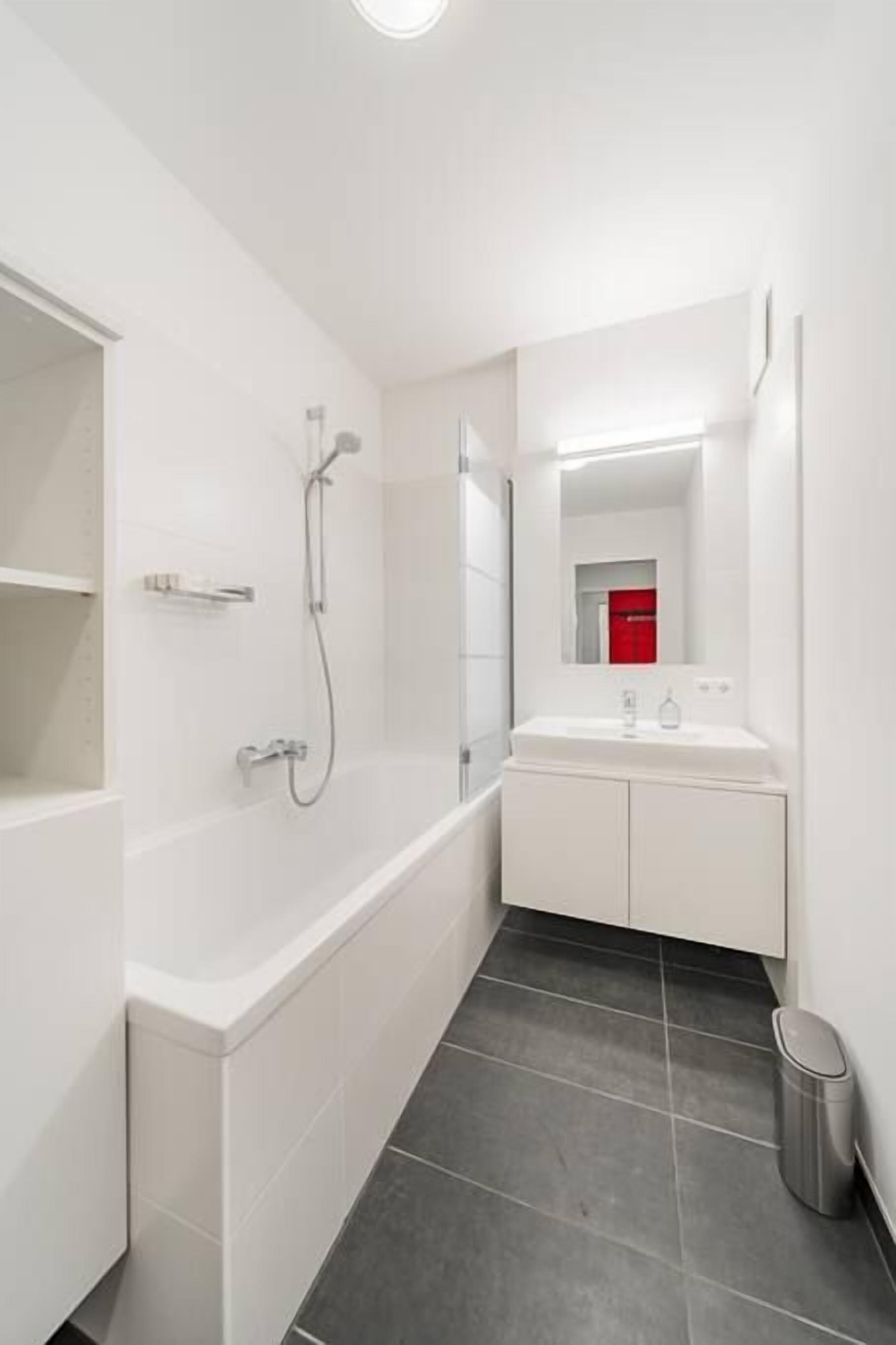 A modern bathroom with a bathtub, a shower, and a sink with a mirror.