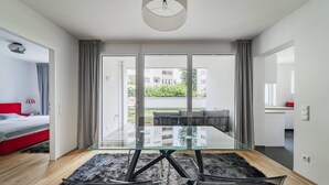 Uma sala de estar moderna com uma mesa de centro de vidro, um sofá vermelho e vista para a cidade através de grandes janelas.