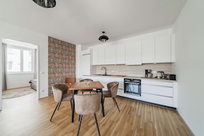 Una cocina moderna con armarios blancos, una mesa de comedor de madera y una pared con diseño.
