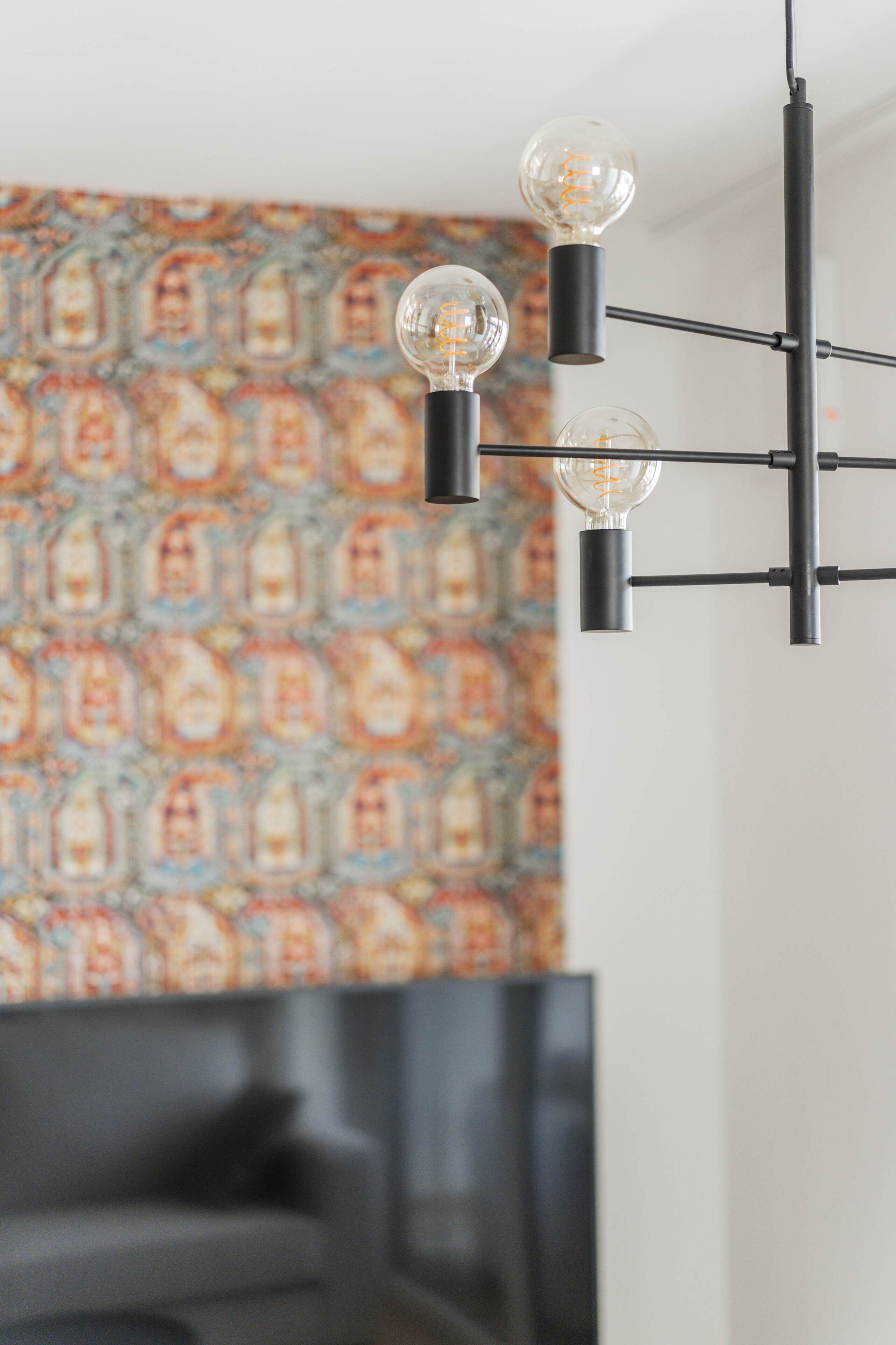 A modern interior with a black metal light fixture and a patterned wall.