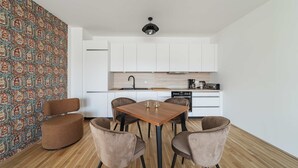 A modern kitchen with white cabinets, a wooden dining table, and four chairs. - 3 Zimmer Apartment mit Blick auf die Stadt (Gmunden)