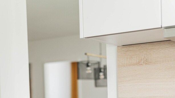 A modern kitchen with white cabinetry and a wooden countertop.