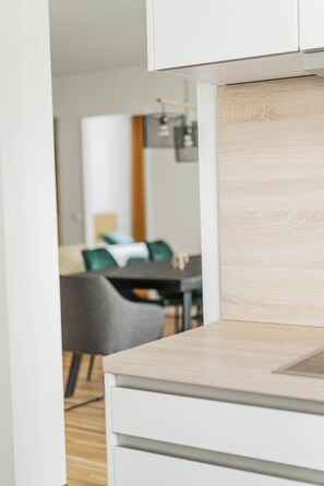 A modern kitchen with white cabinetry and a wooden countertop. - Safran | City view and balcony (Gmunden)