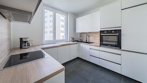 A modern kitchen with a built-in stove, oven, and sink, wooden countertops, and white cabinetry.