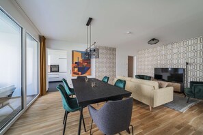 Un espacio moderno para vivir con una mesa de comedor, sillas, un sofá, un televisor y una cocina al fondo.