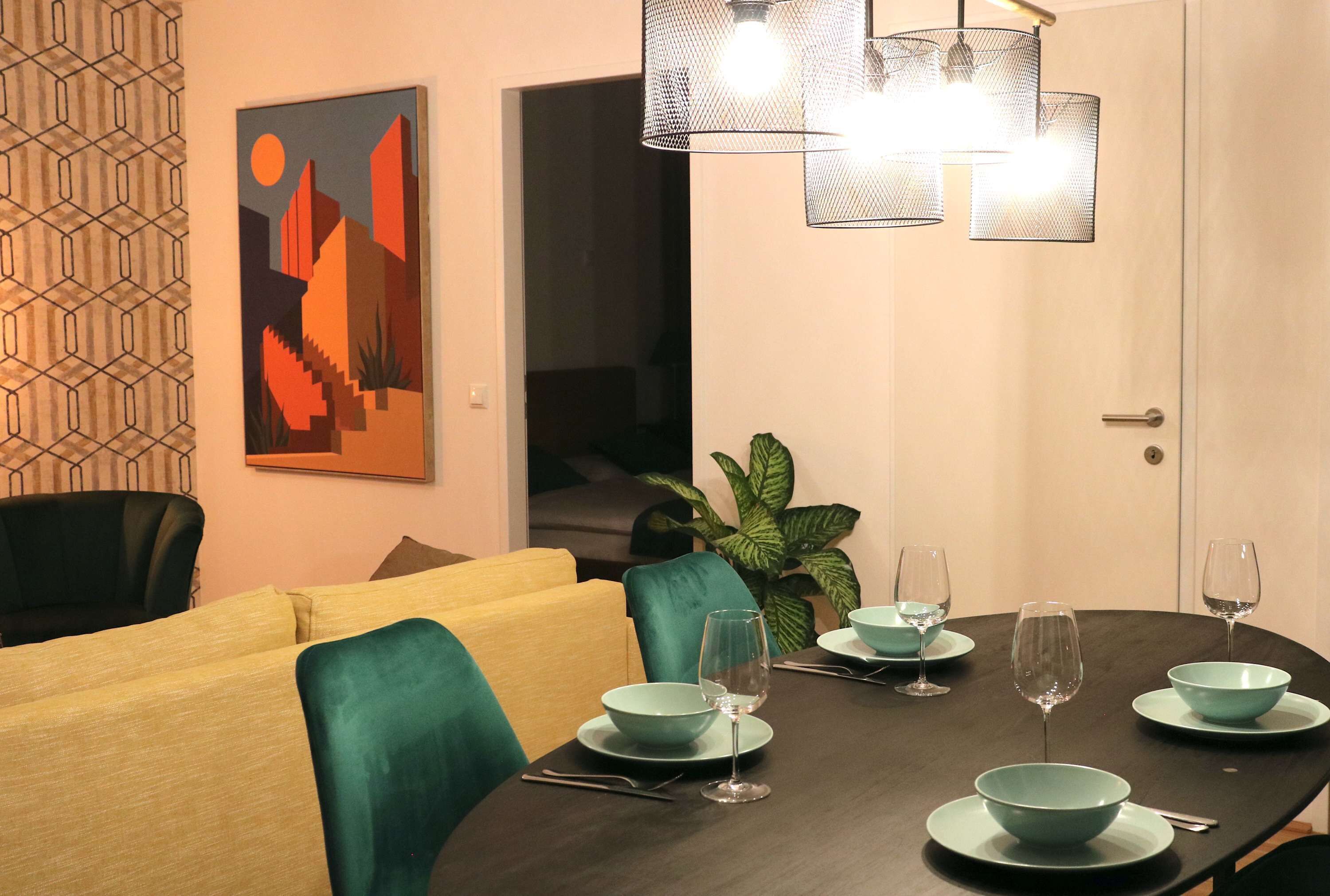A dining area with a dark wooden table, teal chairs, and a geometric painting on the wall.