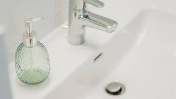 Un lavabo de salle de bain avec un distributeur de savon en verre et une serviette beige.