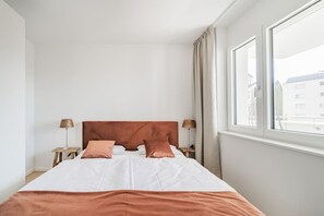 A hotel room with a large bed, two bedside tables with lamps, and a window with curtains. - Two-room apartment with balcony and lake view – Trau(M)seeblick (Gmunden)