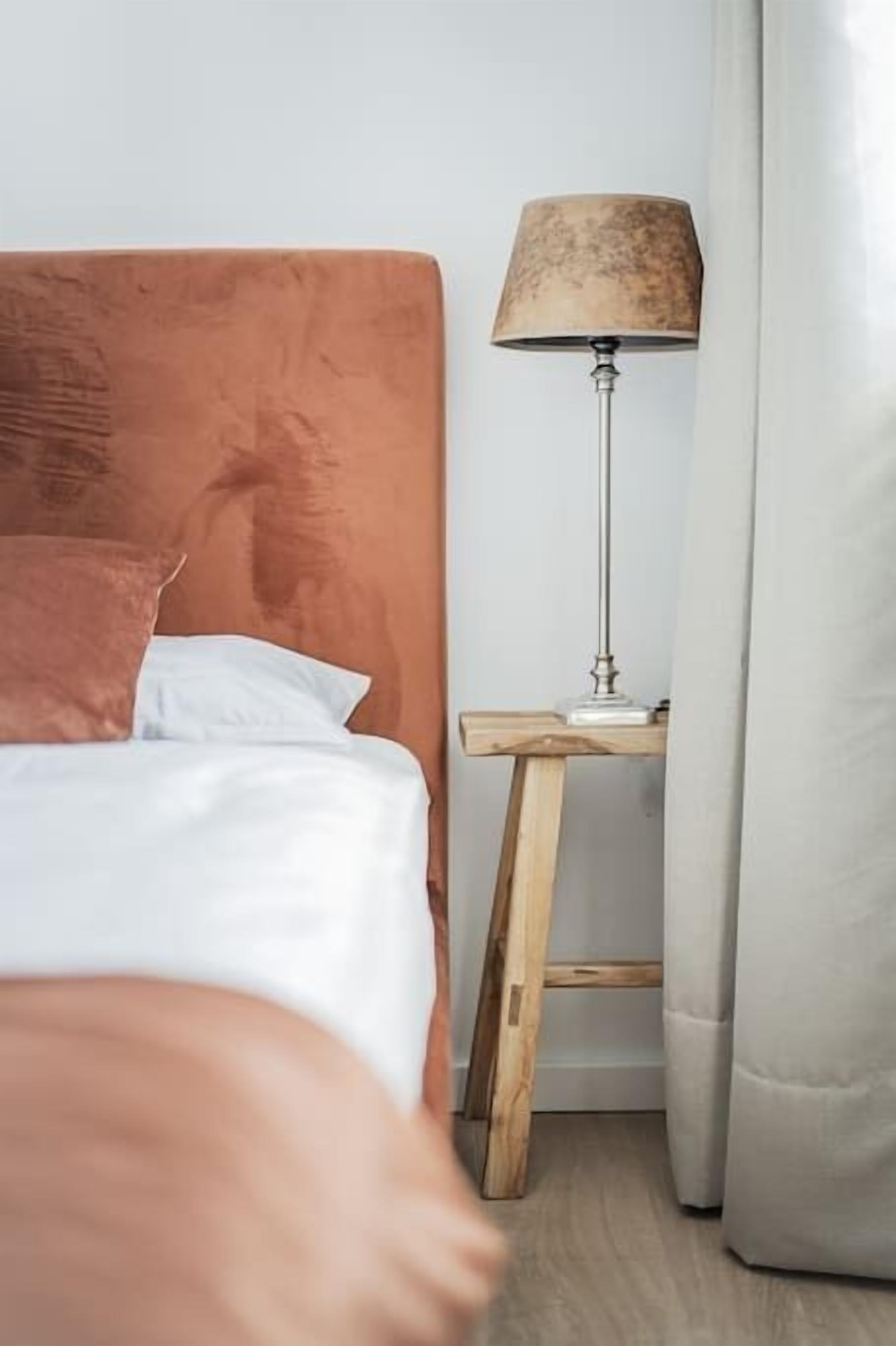 A bedroom with a bed, a nightstand, a lamp, and a curtain.