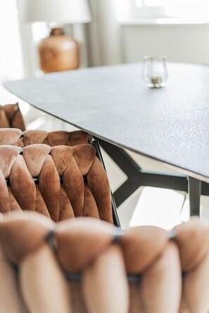 A modern dining table with a geometric metal frame and a glass top. - Two-room apartment with balcony and lake view – Trau(M)seeblick (Gmunden)