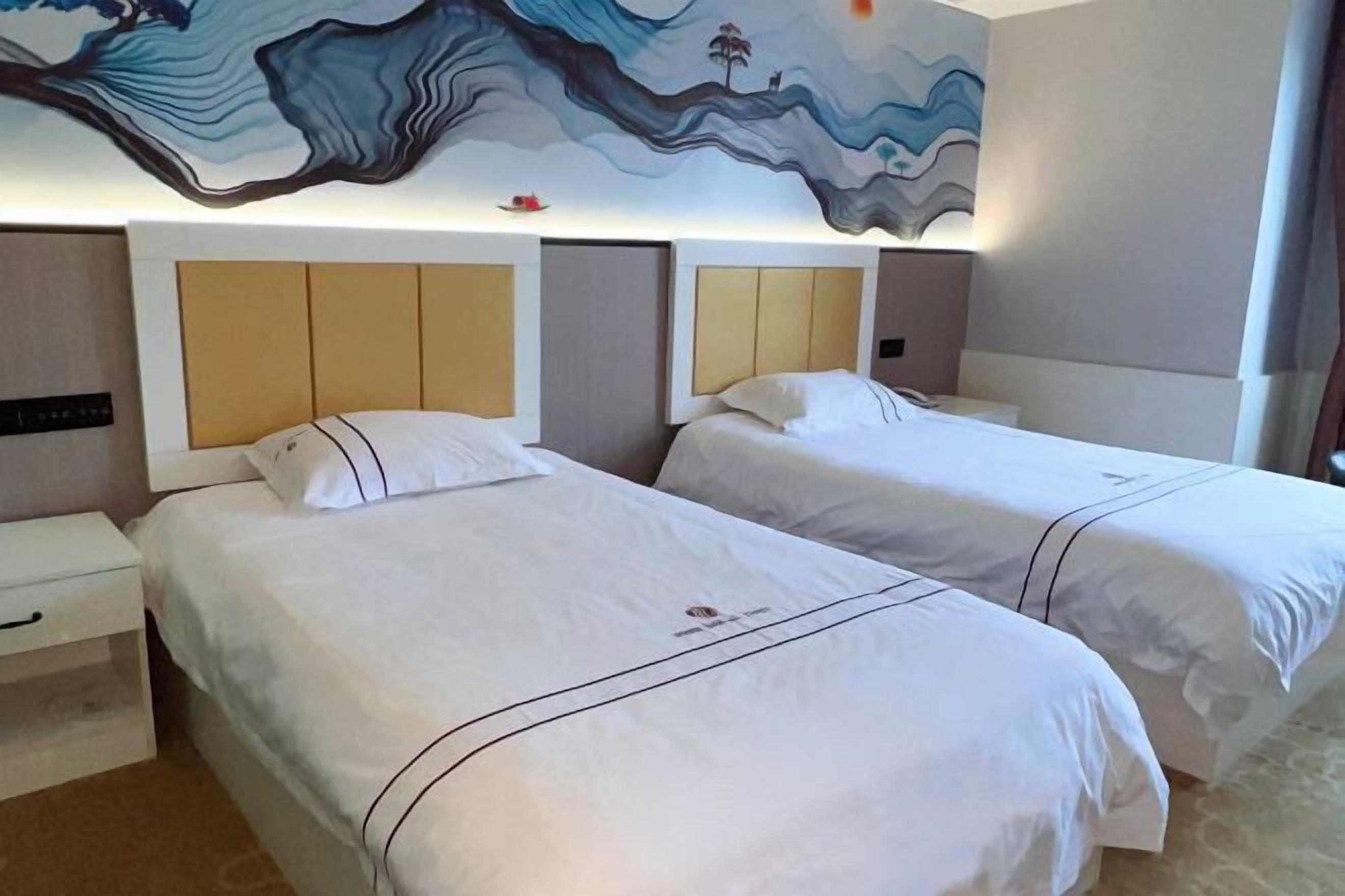Una habitación de hotel con dos camas, cada una con cabecera y mesita de noche. La habitación presenta un cuadro abstracto grande en la pared sobre las camas.