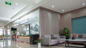 A modern hotel lobby with a reception desk, seating area, and a large window with a view. - Changxing Hainabaichuan Hotel (Changxing)