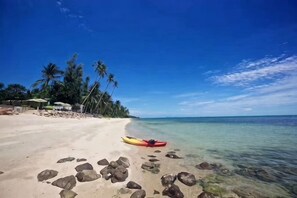 A beach with a clear sky, a red kayak, and palm trees. - Huzhiyun Hotel (Chengjiang)