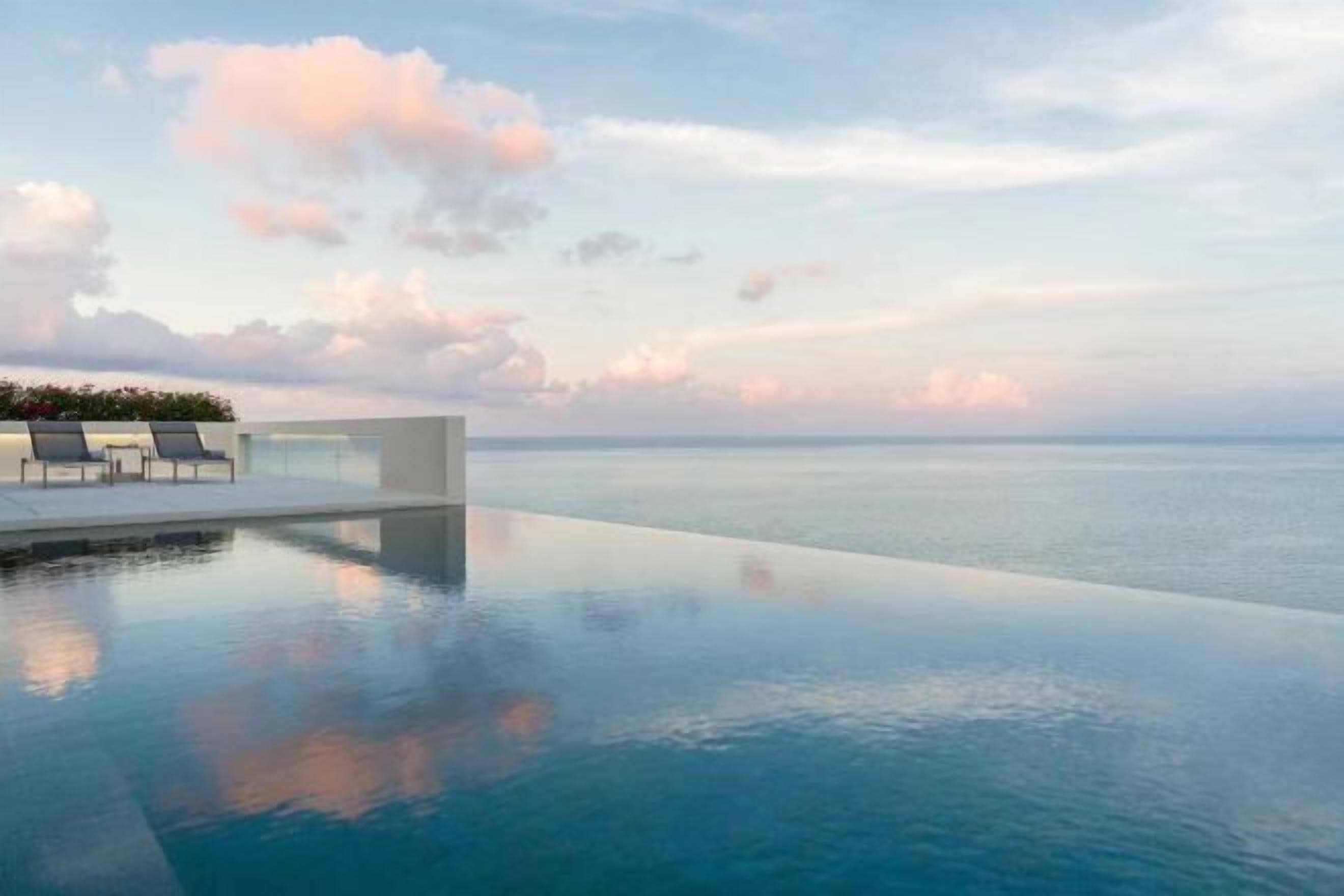 Una piscina infinita con vistas despejadas al mar y un área de estar exterior moderna.