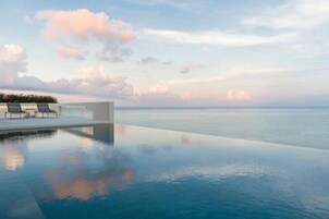 Una piscina infinita con vistas despejadas al mar y un área de estar exterior moderna.