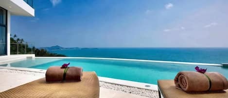 A poolside area with lounge chairs and a view of the sea.