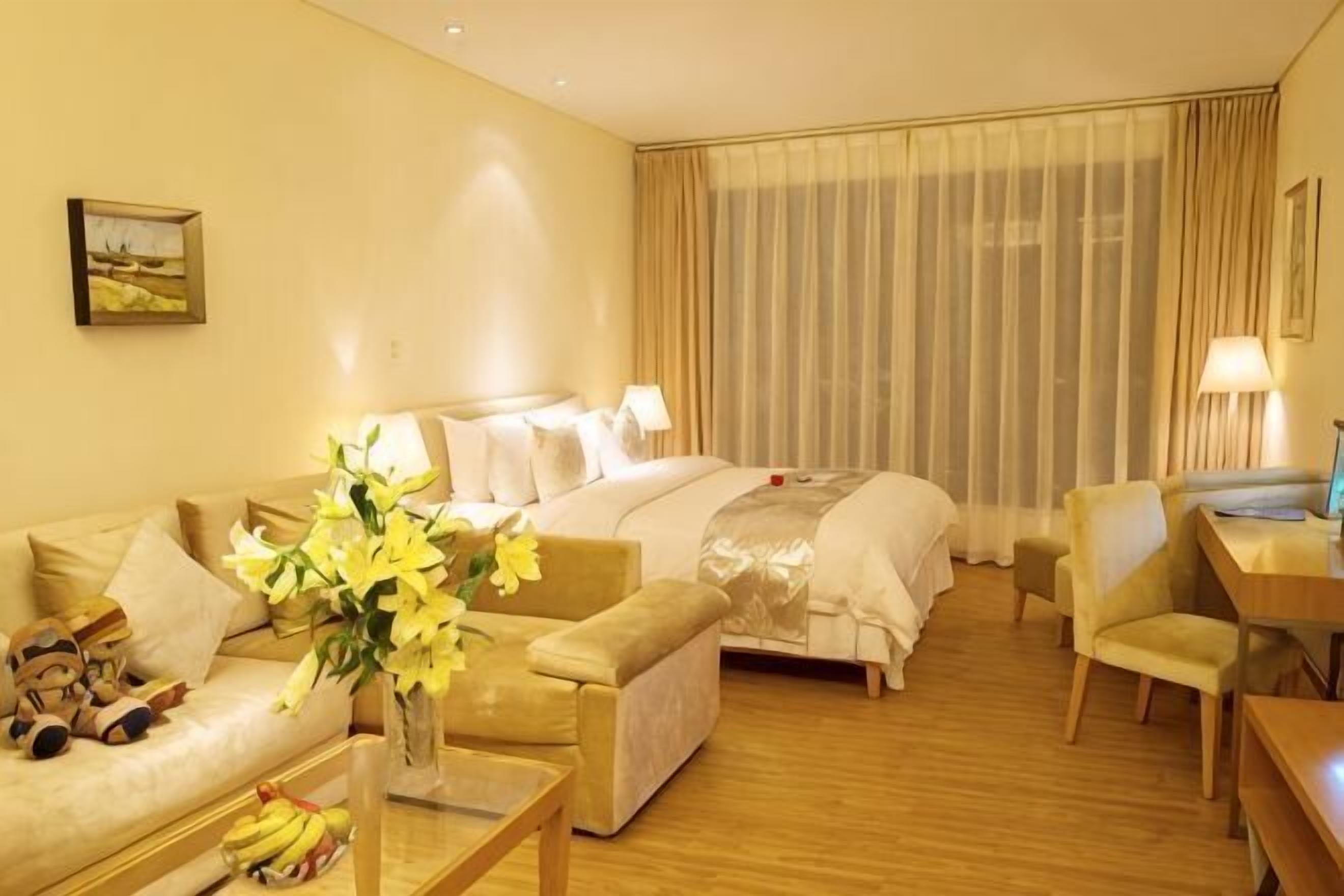 Une chambre d’hôtel avec un lit, un canapé, un bureau et une chaise.