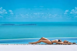Une personne allongée sur une plage, avec vue sur l’océan et une île au loin.