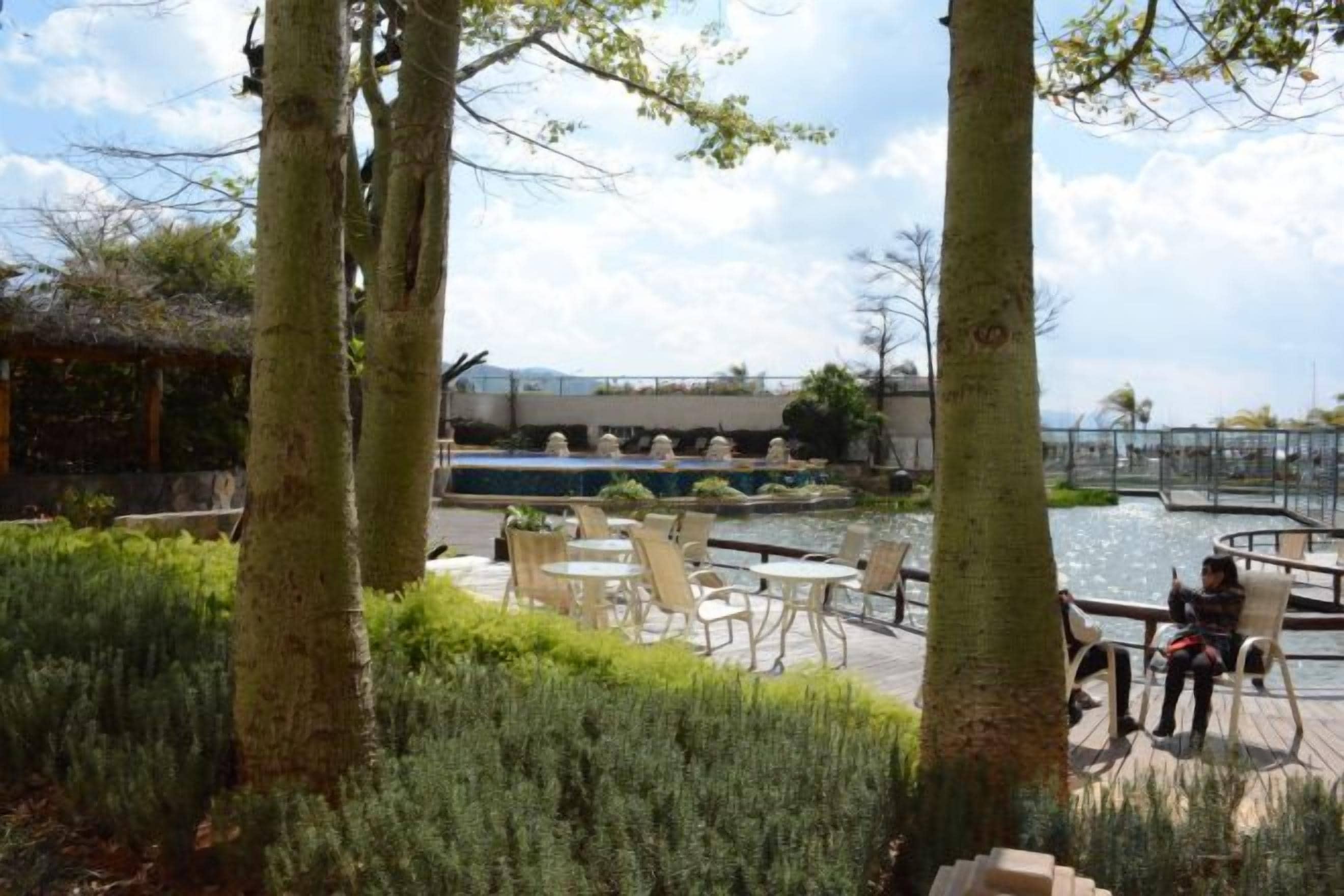 An outdoor seating area with tables and chairs, a water feature, and trees.