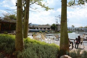 An outdoor seating area with tables and chairs, a water feature, and trees. - Huzhiyun Hotel (Chengjiang)