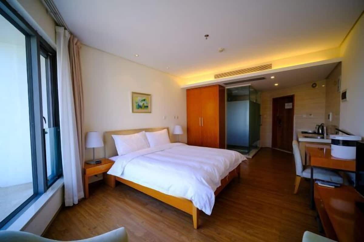 Een hotelkamer met een groot bed, een bureau, een stoel en een raam met gordijnen.