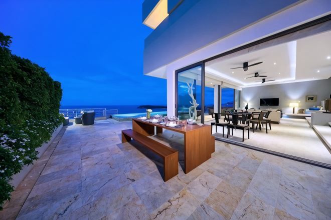 Un espacio exterior moderno con comedor, piscina y vistas al océano.