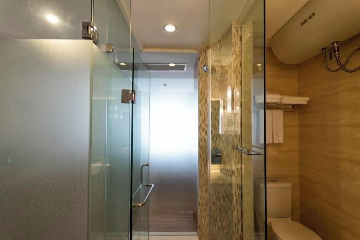 A modern bathroom with a glass shower enclosure, a toilet, and a towel rack.