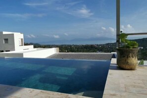 Una piscina al terrat amb una vista clara del paisatge urbà i les muntanyes a la distància.